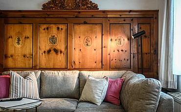 Die Couch vor stilvoller Holzverkleidung auf der Wand im Cottage Family des Pechtlguts in Lofer