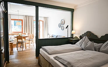 A cozy bed with a wooden frame in the Studio at the Pechtlgut main house in Lofer