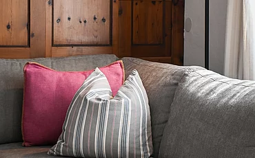 Die Couch vor stilvoller Holzverkleidung auf der Wand im Cottage Family des Pechtlguts in Lofer