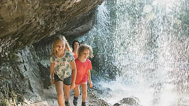 Eine Familie wandert unter einem Wasserfall durch