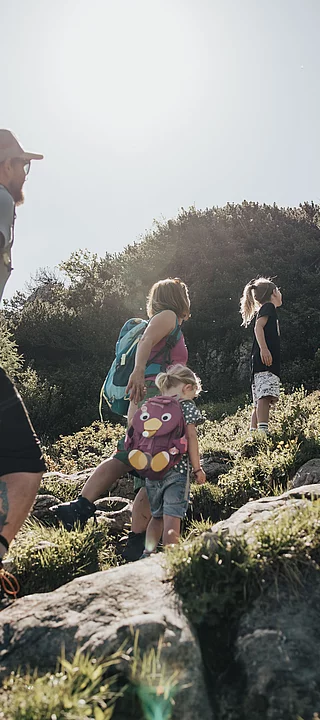 A family is hiking on a mountain in the sunshine