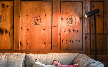 Die Couch vor stilvoller Holzverkleidung auf der Wand im Cottage Family des Pechtlguts in Lofer