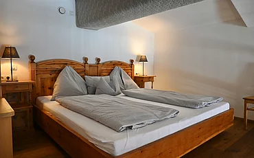 A cozy bed with a wooden frame in the Gallery, the main building of the Pechtlgut in Lofer