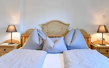 Ein gemütliches Bett im Family Haupthaus des Pechtlguts in Lofer