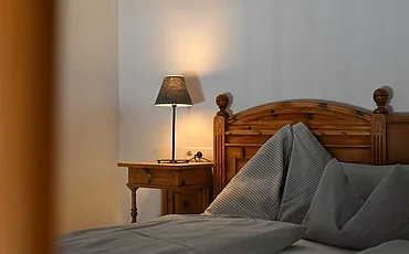A cozy bed with a wooden frame in the Gallery, the main building of the Pechtlgut in Lofer