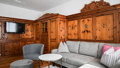 Die Couch vor stilvoller Holzverkleidung auf der Wand im Cottage Family des Pechtlguts in Lofer