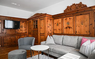 Die Couch vor stilvoller Holzverkleidung auf der Wand im Cottage Family des Pechtlguts in Lofer
