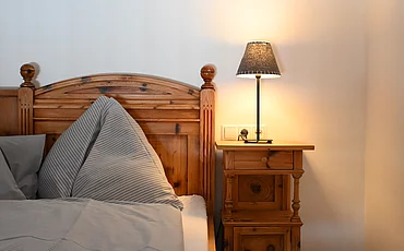 A cozy bed with a wooden frame in the Gallery, the main building of the Pechtlgut in Lofer
