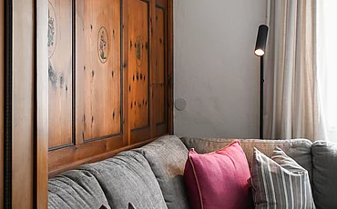 Die Couch vor stilvoller Holzverkleidung auf der Wand im Cottage Family des Pechtlguts in Lofer