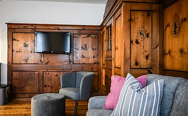 Die Couch vor stilvoller Holzverkleidung auf der Wand im Cottage Family des Pechtlguts in Lofer