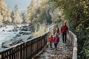 A family on a wooden boardwalk next to the Saalach River in Lofer