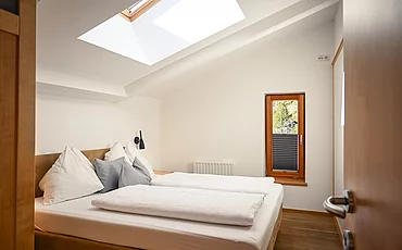 Ein gemütliches Bett im Family Haupthaus des Pechtlguts in Lofer