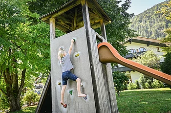 A child climbs onto a playhouse with a slide in the garden of the Pechtlgut in Lofer