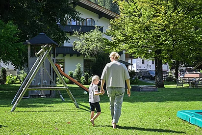 Eine Mutter geht mit ihrem Kind durch den Garten des Pechtlguts in Lofer