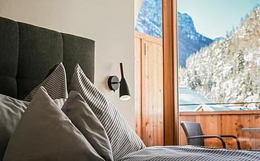 Gemütliches Bett mit Ausblick auf die Berge im Haupthaus Family Plus des Pechtlguts in Lofer