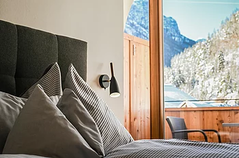 Gemütliches Bett mit Ausblick auf die Berge im Haupthaus Family Plus des Pechtlguts in Lofer
